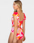 A woman modeling a two-piece swimsuit from the back, featuring a vibrant abstract floral pattern in pink, orange, and white, with ruffled cap sleeves and a low open back.