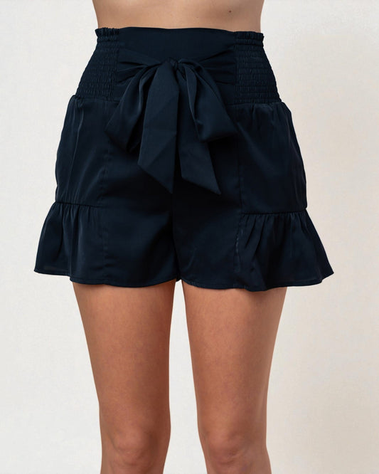 Black shorts with a bow detail on a plain background