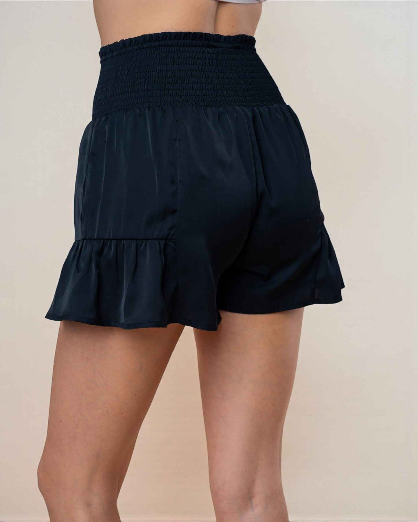 Black shorts worn by a person on a beige background