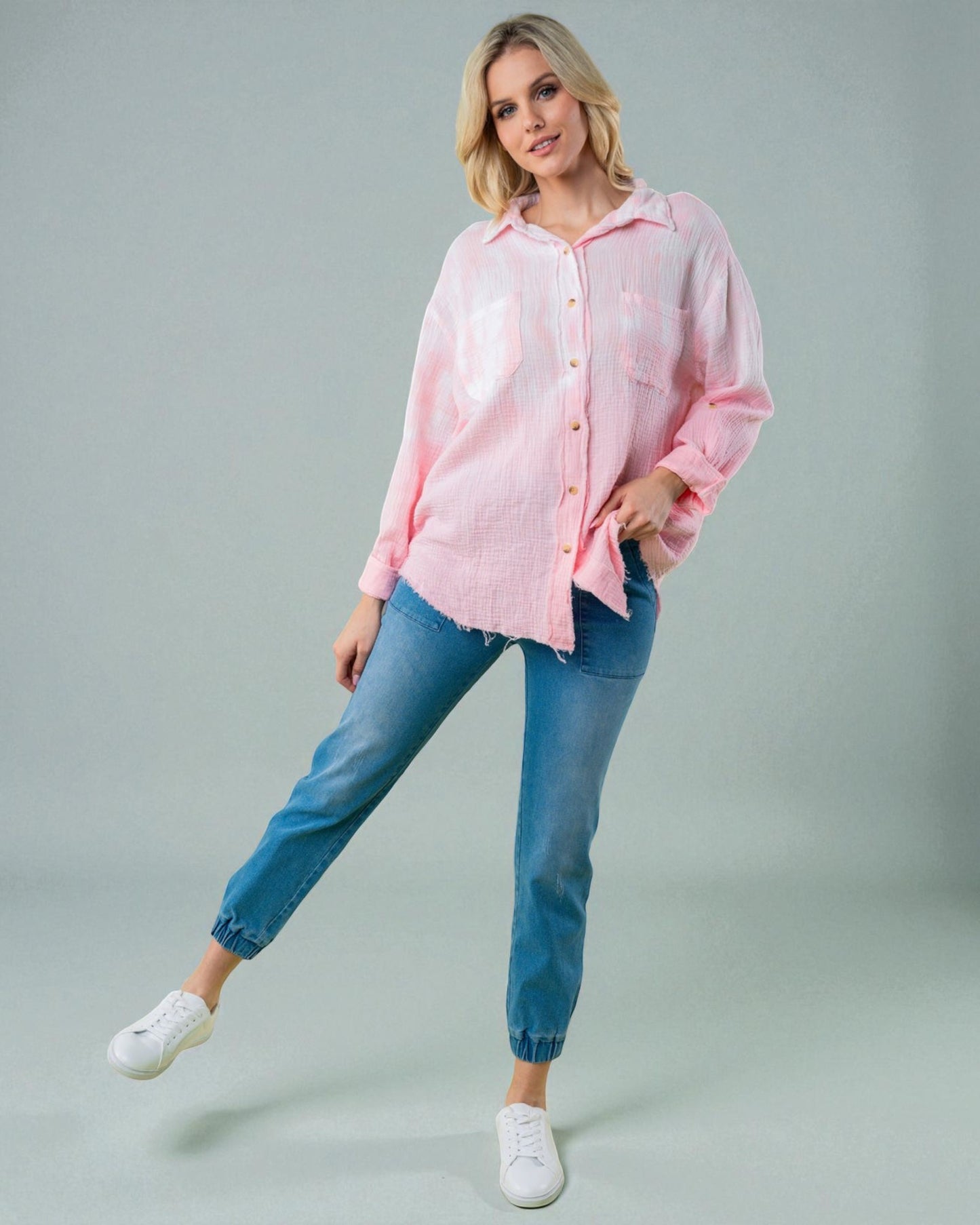 Woman wearing a pink shirt and blue jeans on a gray background