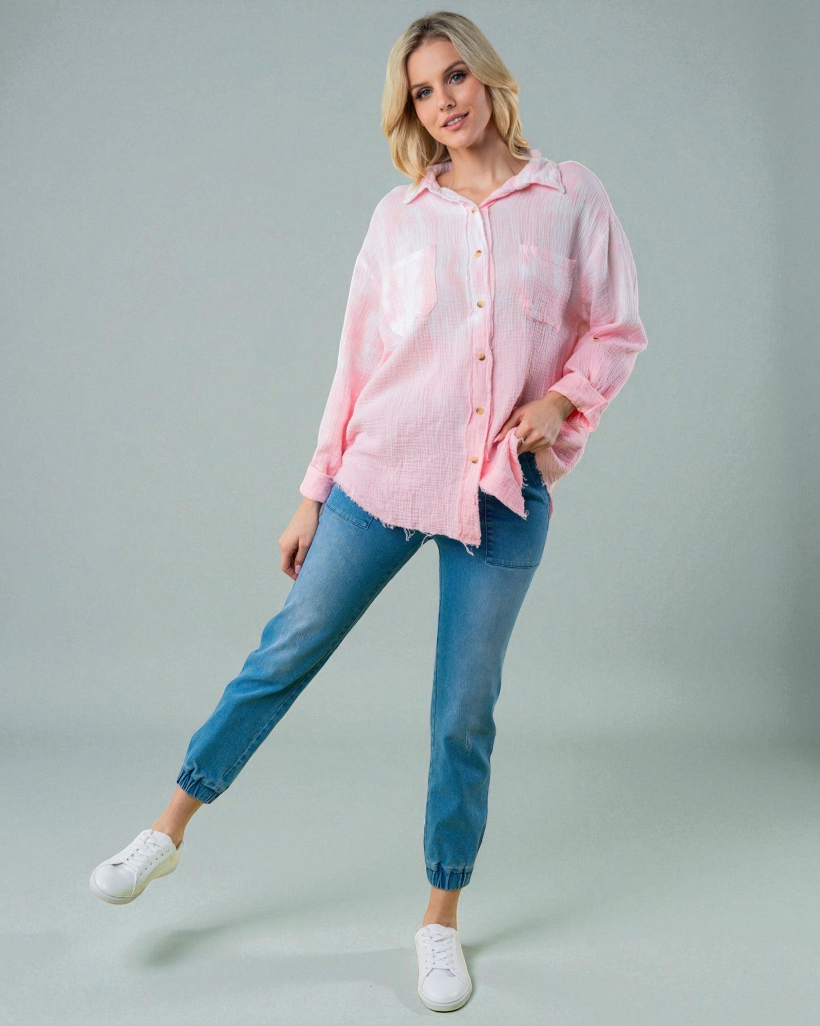 Woman wearing a pink shirt and blue jeans on a gray background