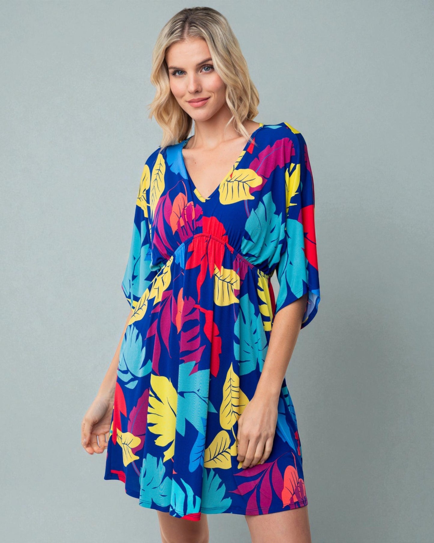 Woman wearing a colorful tropical pattern dress on a gray background