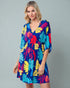Woman wearing a colorful tropical pattern dress on a gray background
