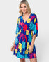 Woman wearing a colorful tropical pattern dress on a white background