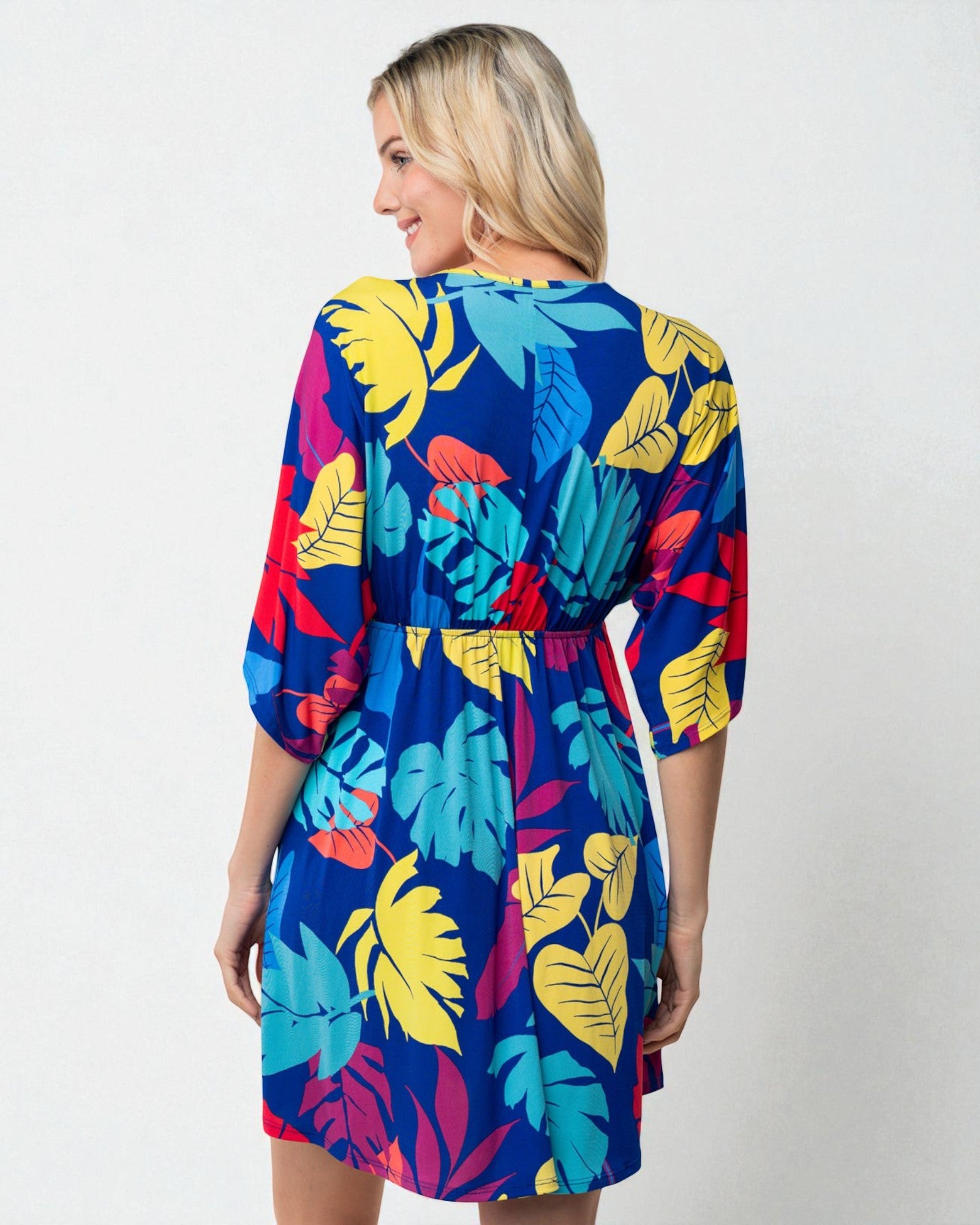 Woman wearing a colorful tropical leaf pattern dress on a white background