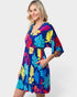 Woman wearing a colorful tropical leaf pattern dress on a white background