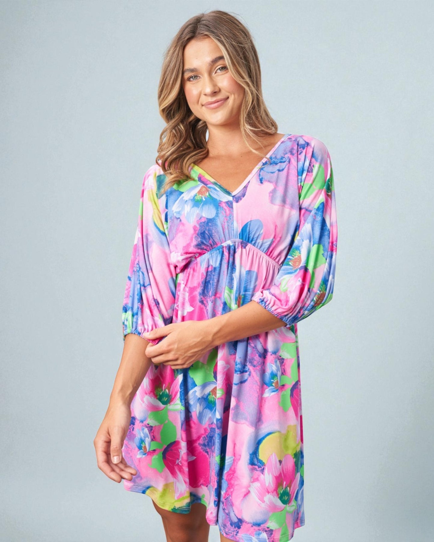 Woman wearing a colorful dress with a floral pattern on a gray background