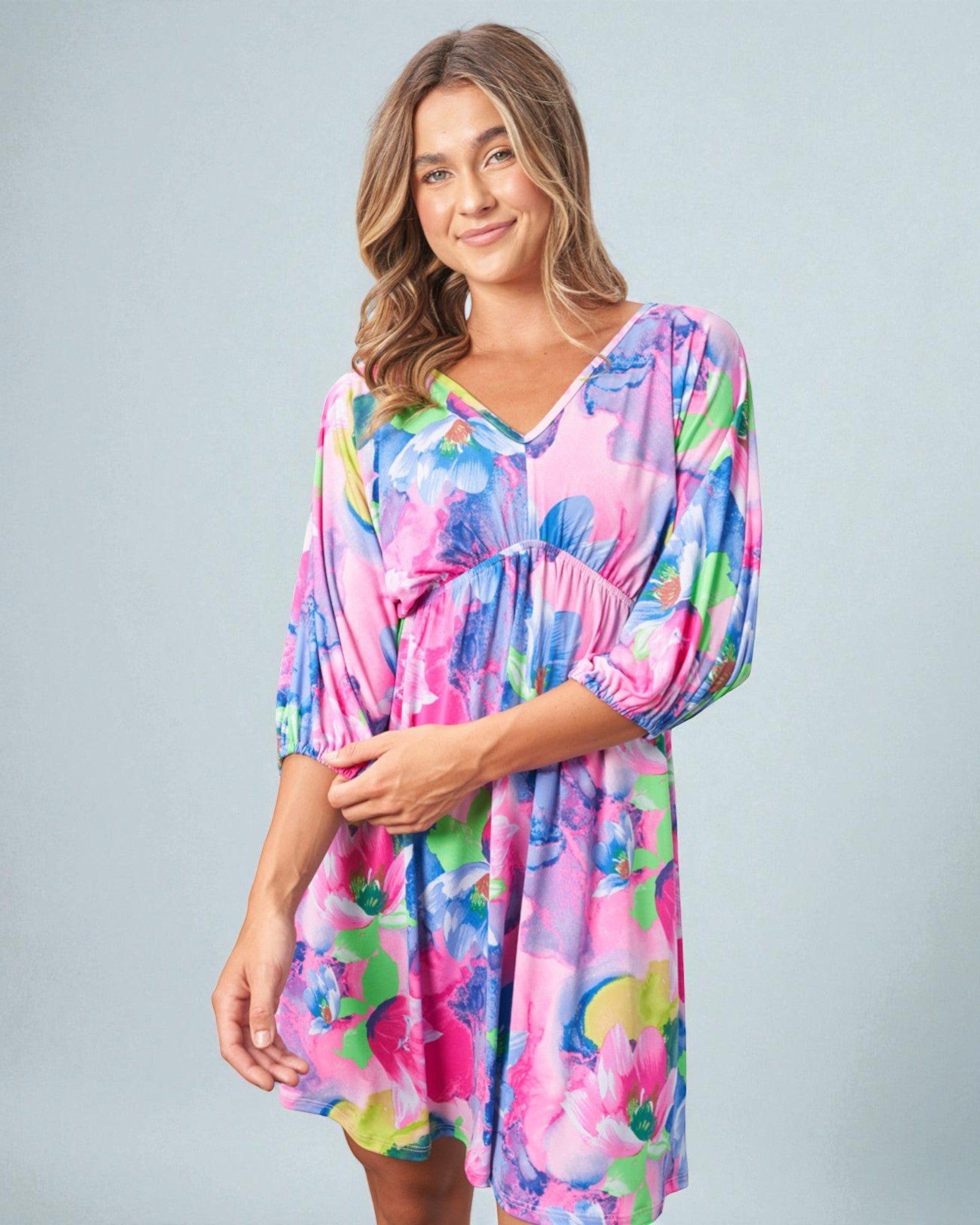 Woman wearing a colorful dress with a floral pattern on a gray background