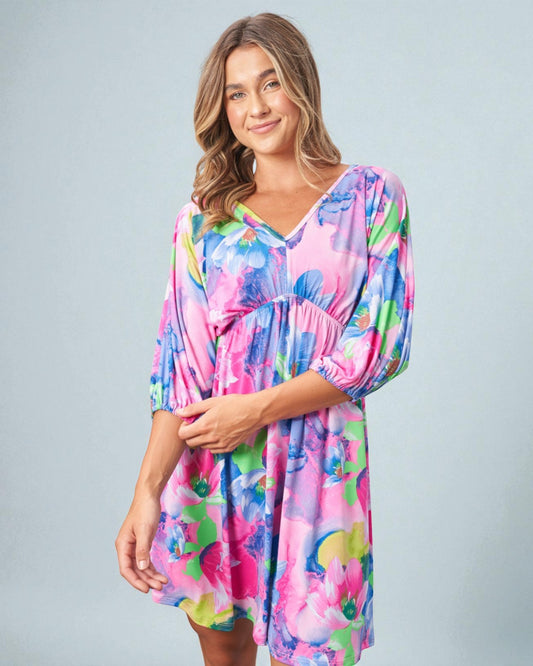 Woman wearing a colorful dress with a floral pattern on a gray background