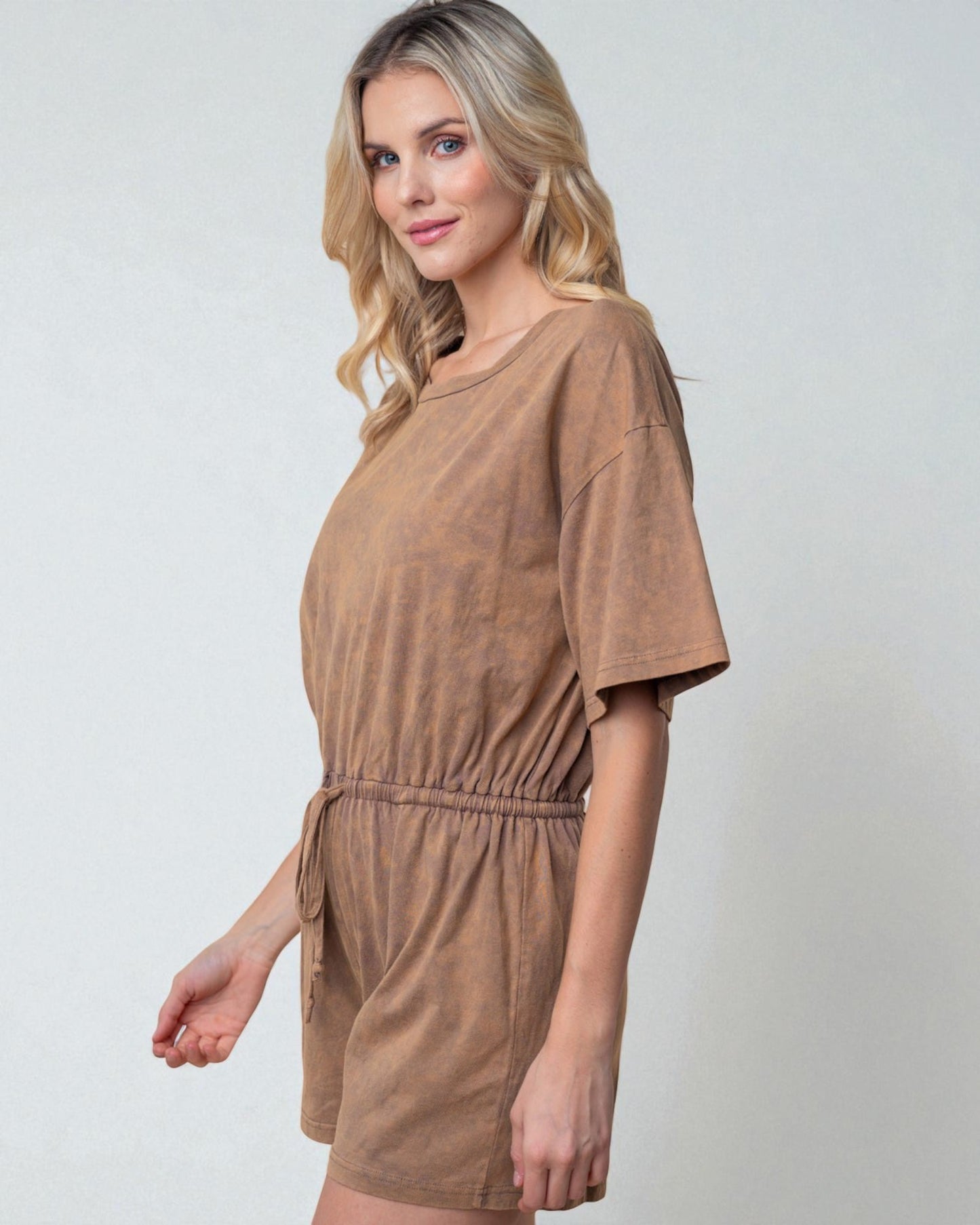 Woman wearing a brown romper against a plain background