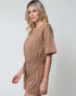 Woman wearing a brown romper against a plain background