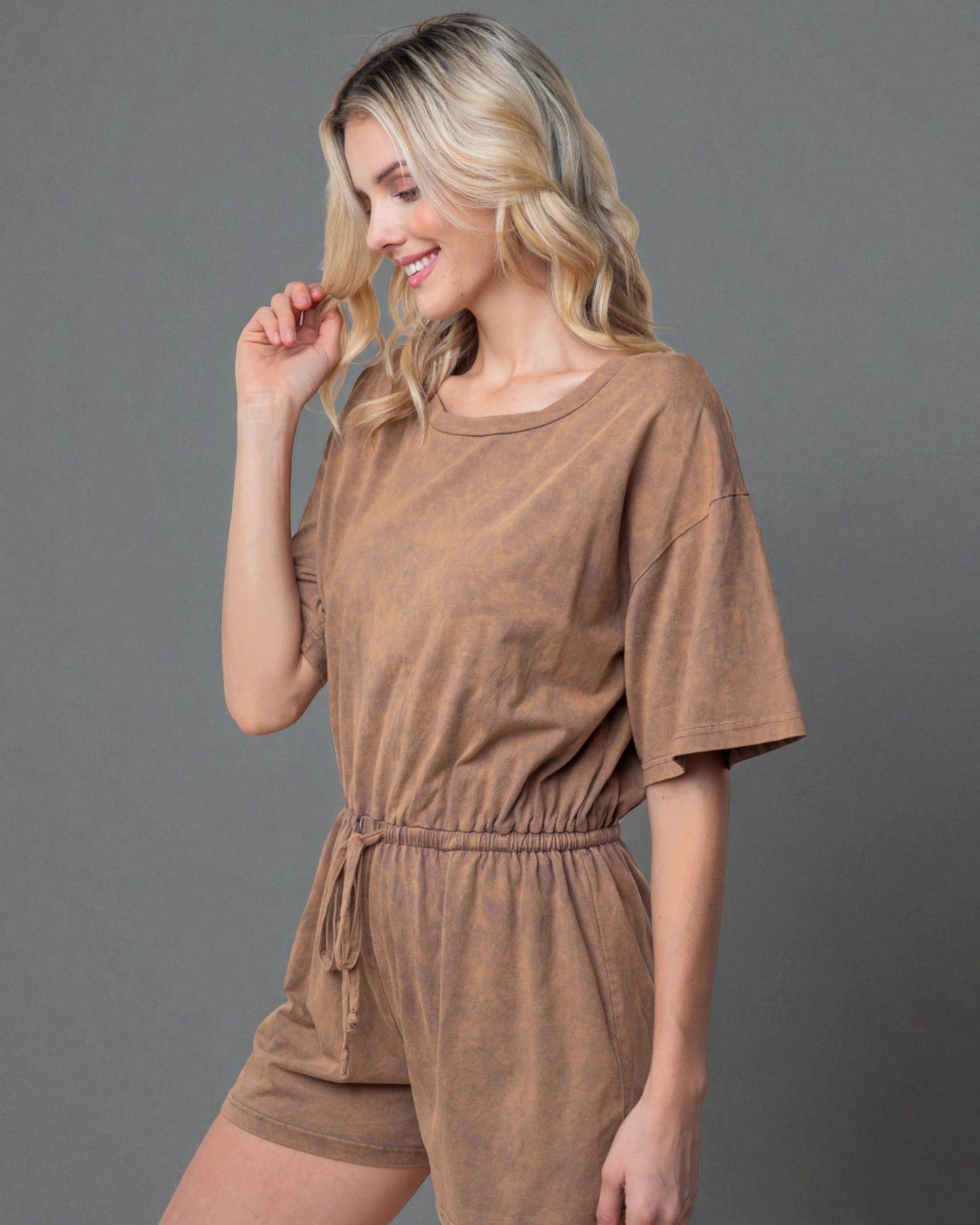 Woman wearing a brown romper against a gray background
