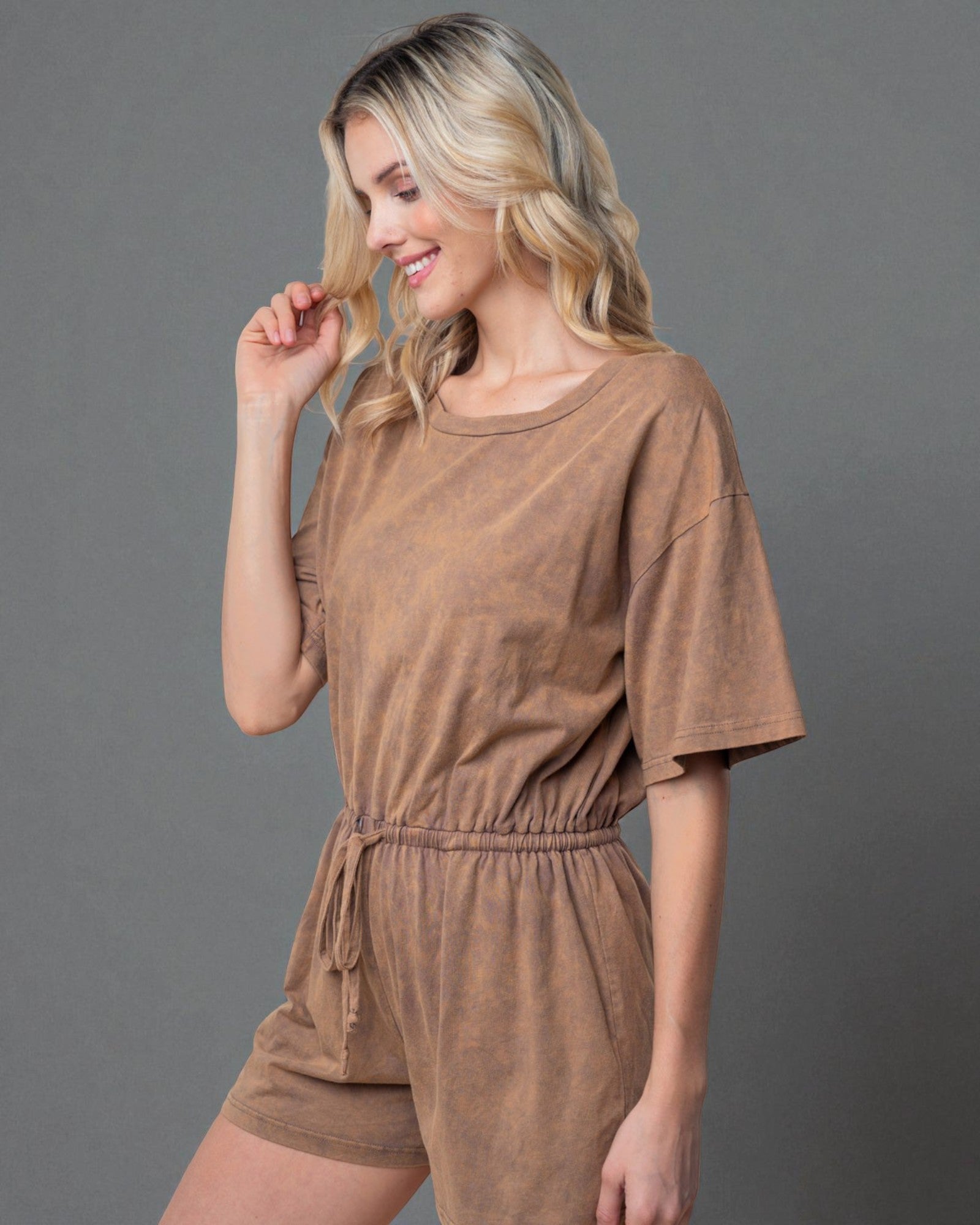 Woman wearing a brown romper against a gray background