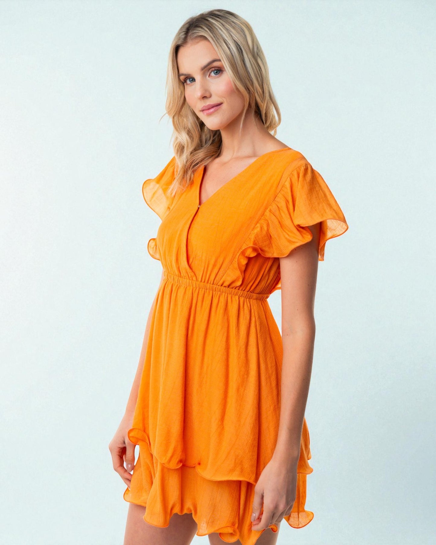 Woman wearing an orange dress against a light blue background