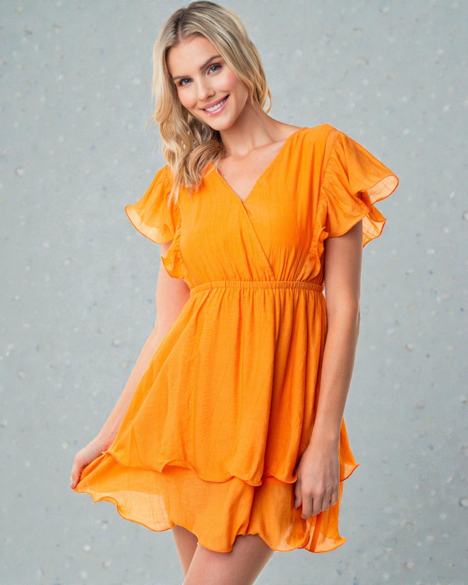 Woman wearing an orange dress against a gray background