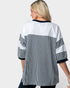A woman shown from the back wearing an oversized short-sleeve top with a color-blocked design: white upper back and shoulders, black-and-white vertical stripes across the center and sleeves, and black trim at the neckline and sleeve cuffs, against a light gray studio background.