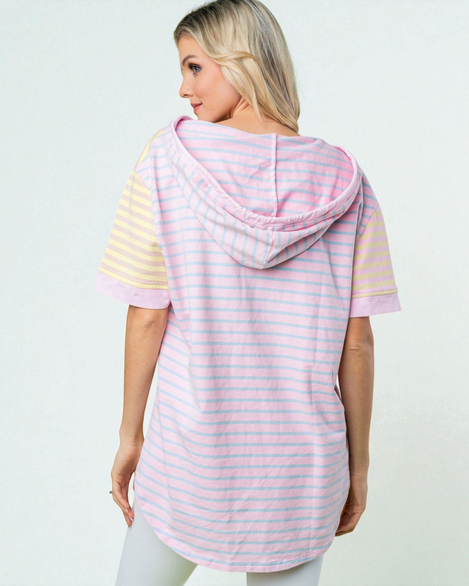Woman wearing a pink and yellow striped hoodie on a light gray background