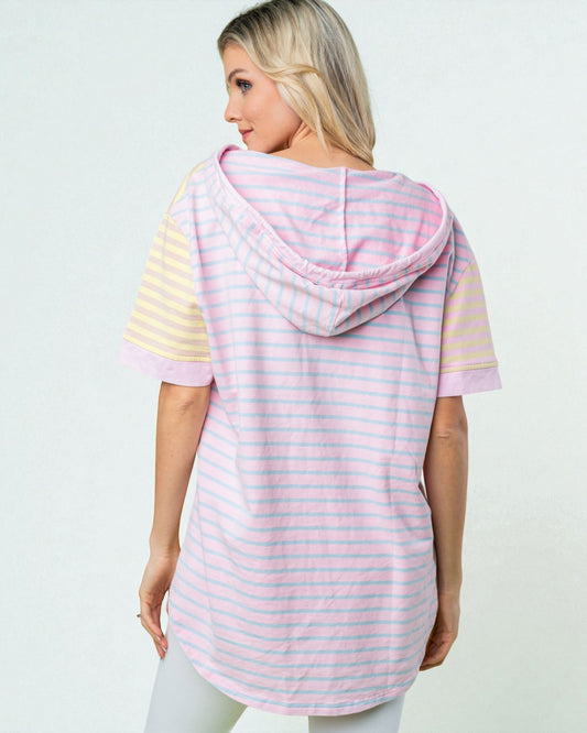 Woman wearing a pink and yellow striped hoodie on a light gray background