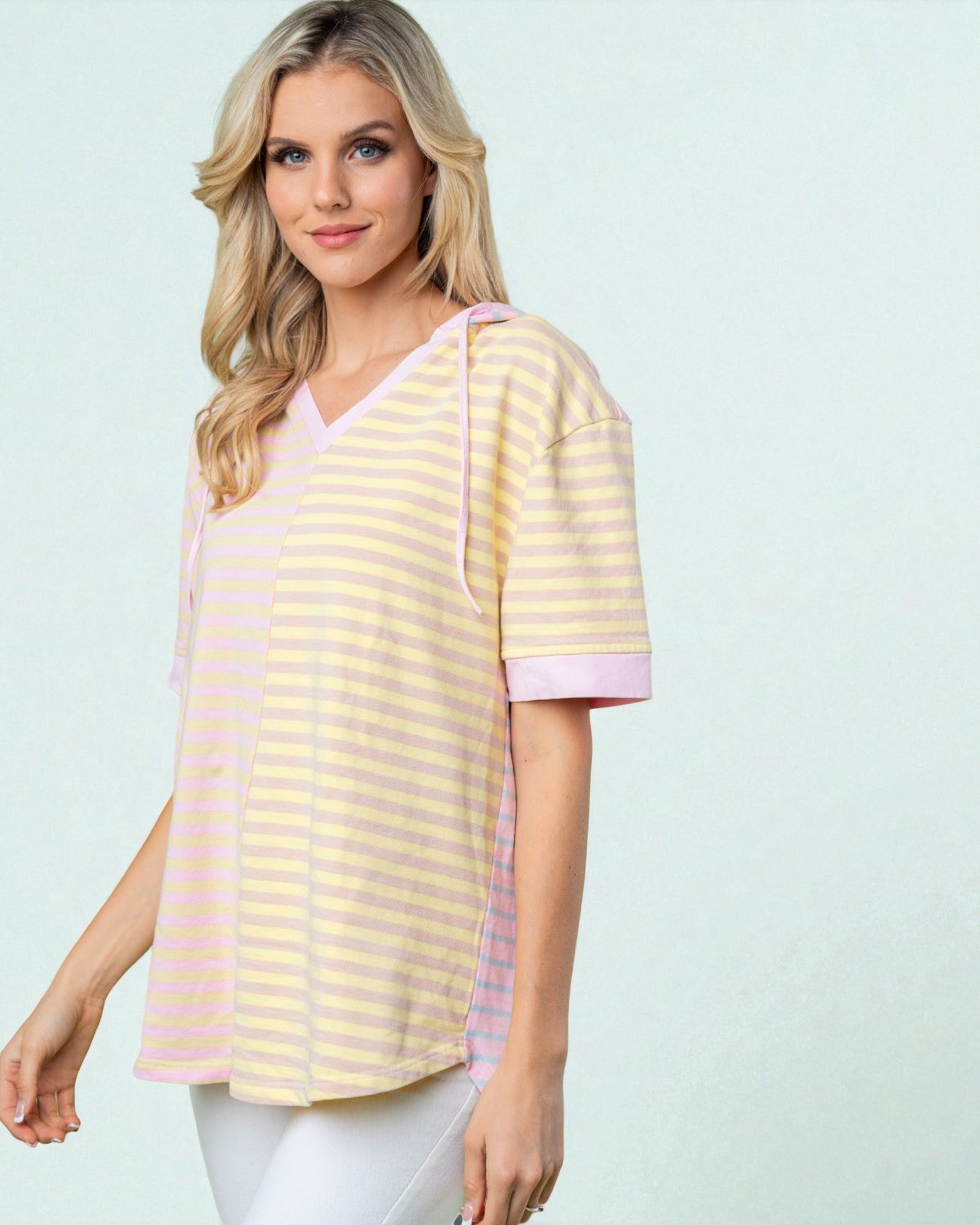 Woman wearing a yellow and pink striped shirt against a light blue background
