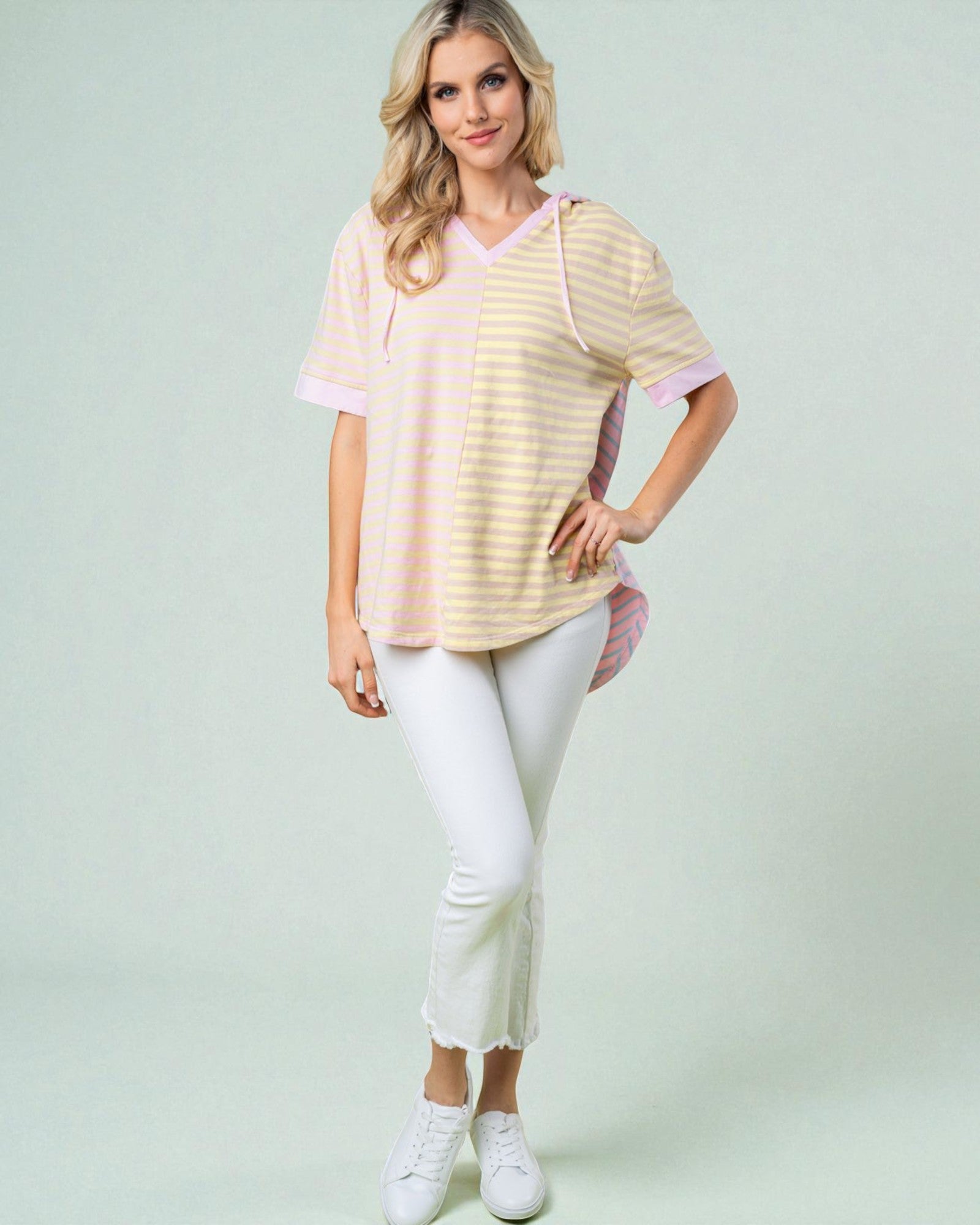 Woman wearing a striped shirt and white pants on a light green background