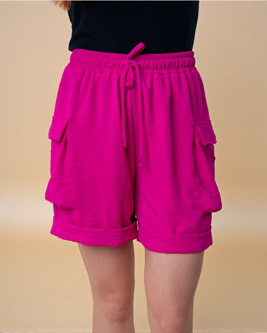 Person wearing bright pink shorts on a beige background