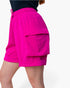 Bright pink cargo shorts with a drawstring waist and a large side flap pocket, shown on a model against a plain light background.