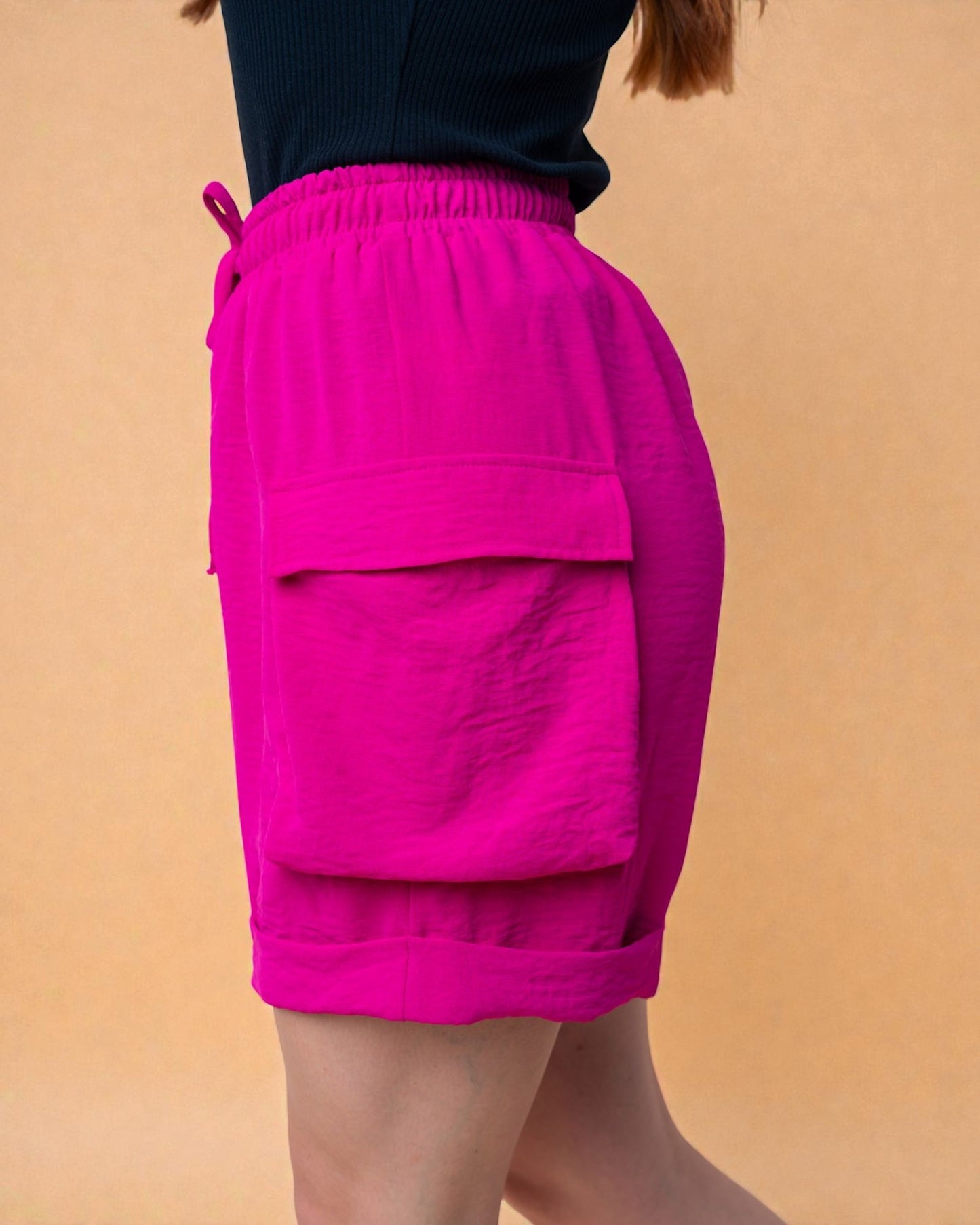 Person wearing bright pink shorts on a beige background