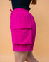 Person wearing bright pink shorts on a beige background