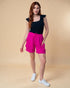 Woman wearing a black top and pink shorts on a beige background