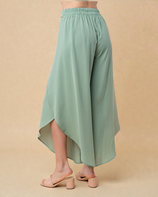 Green wide-leg pants worn by a person on a beige background