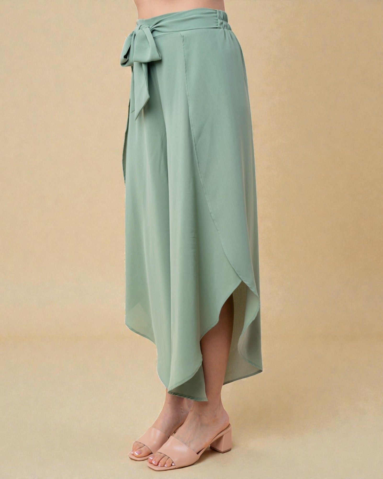 Sage green wrap skirt worn by a person on a beige background