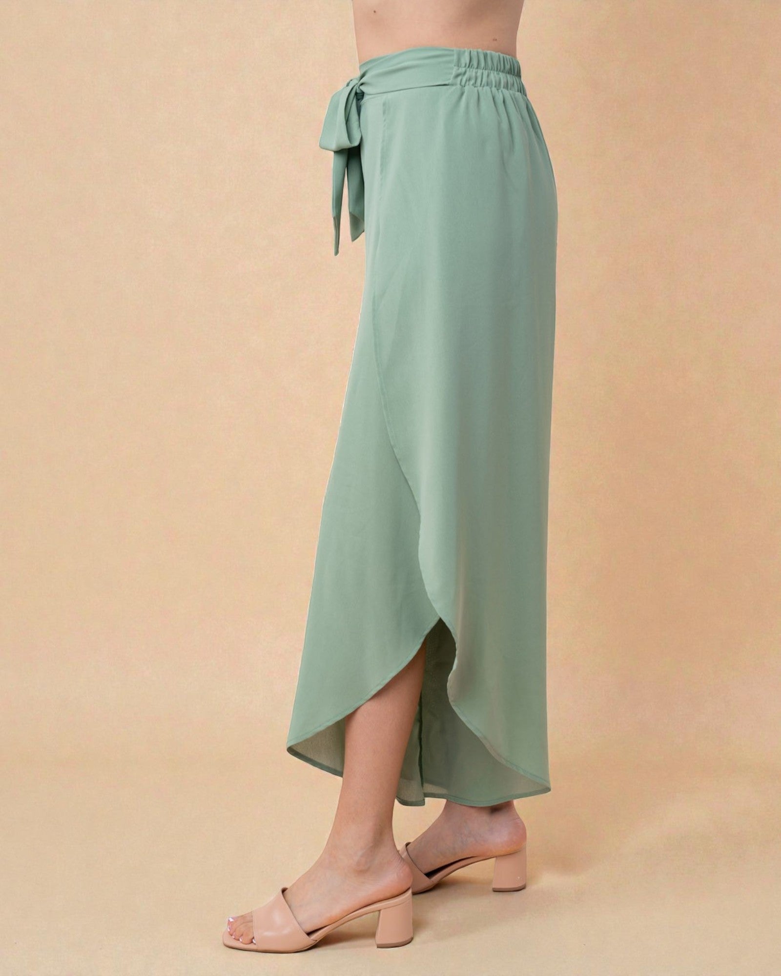 Green wrap skirt worn by a person on a beige background