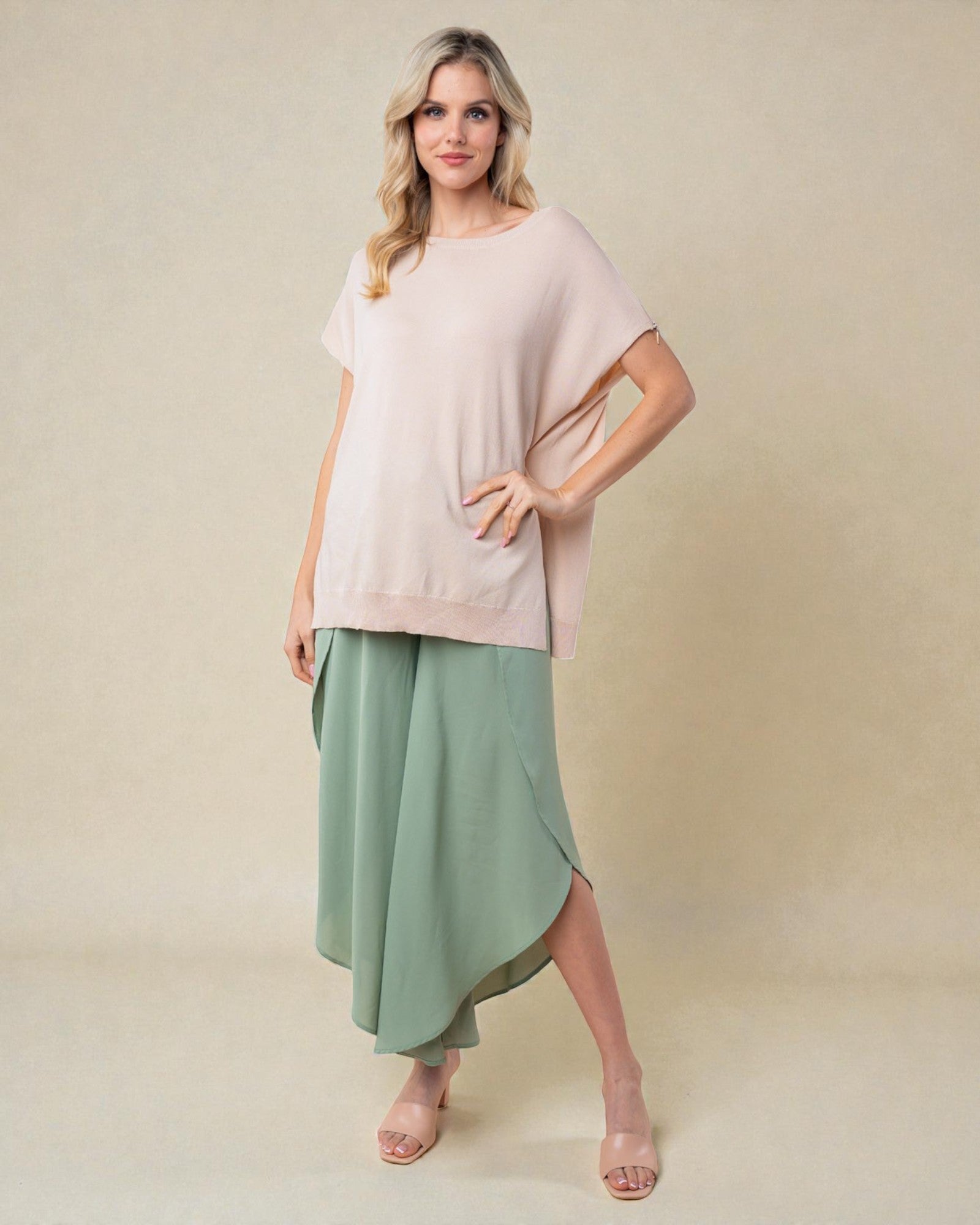 Woman wearing a light pink top and green skirt on a beige background