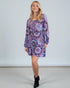 Woman wearing a purple patterned dress on a plain background