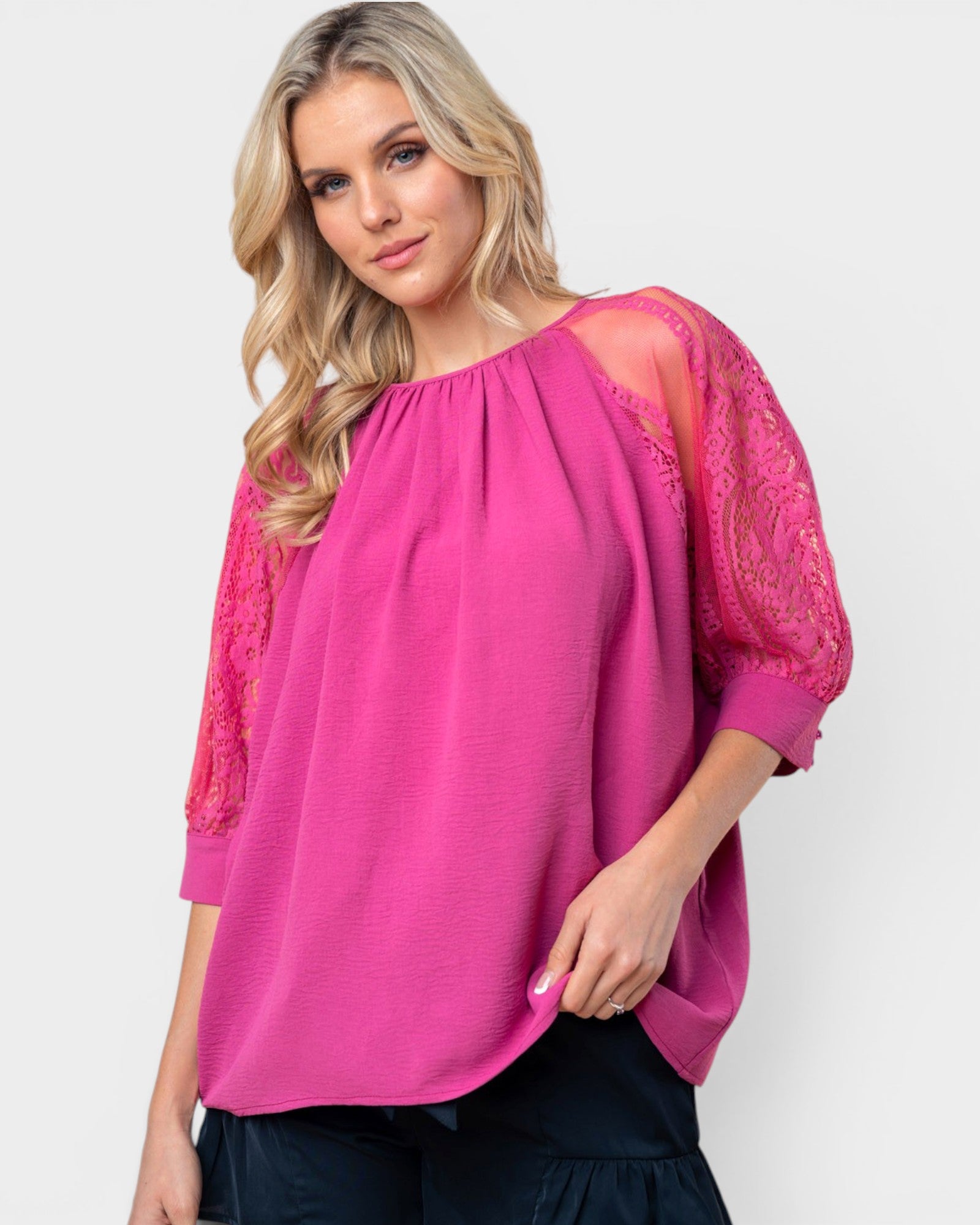 Woman wearing a pink blouse with lace sleeves on a white background