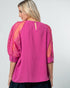 Woman wearing a pink blouse with sheer sleeves on a white background