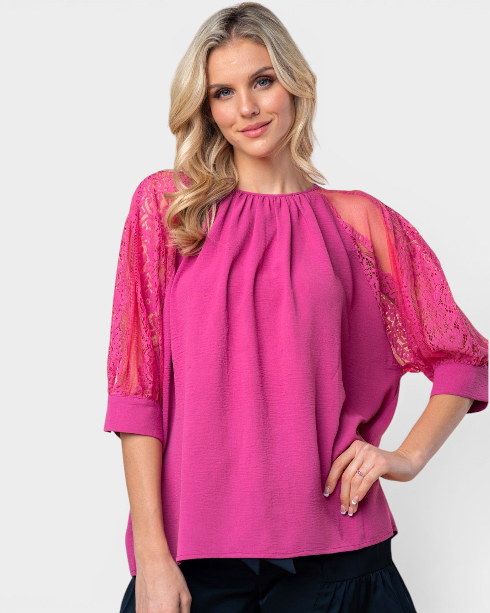 Woman wearing a pink blouse with lace sleeves on a white background