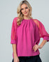 Woman wearing a pink blouse with lace sleeves on a gray background