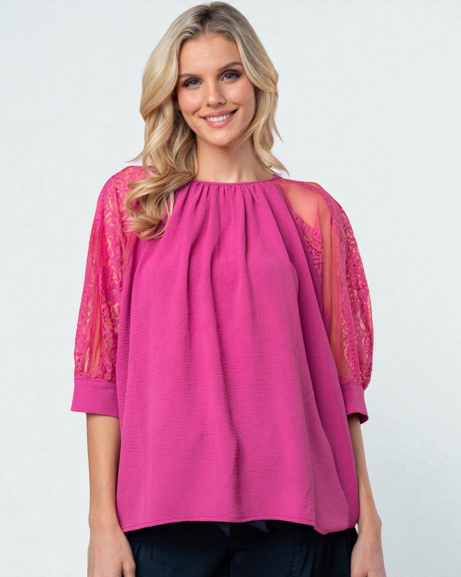 Woman wearing a pink blouse with sheer sleeves on a white background