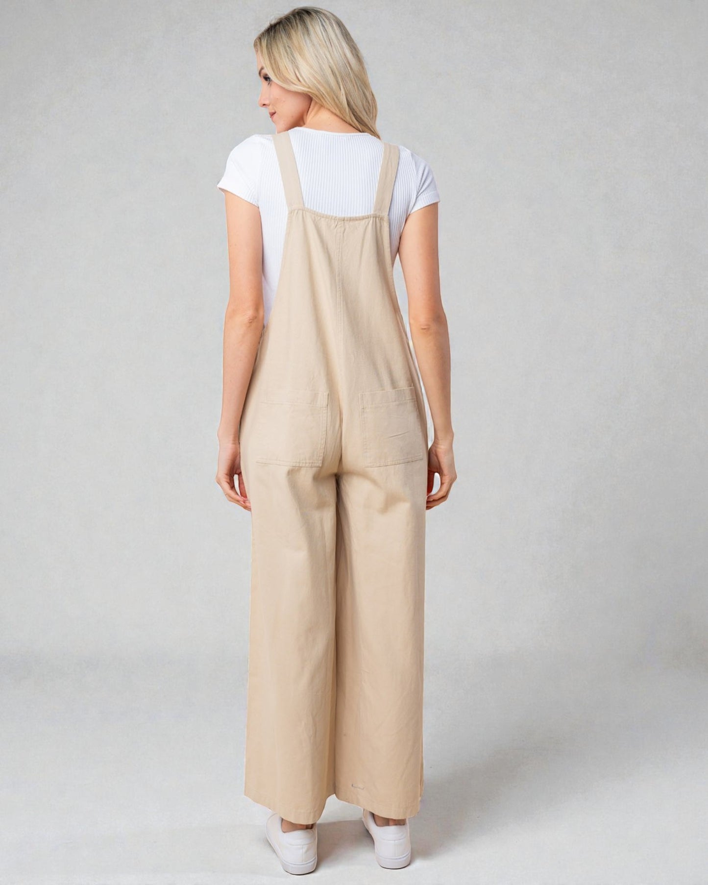 Woman wearing beige overalls on a plain background