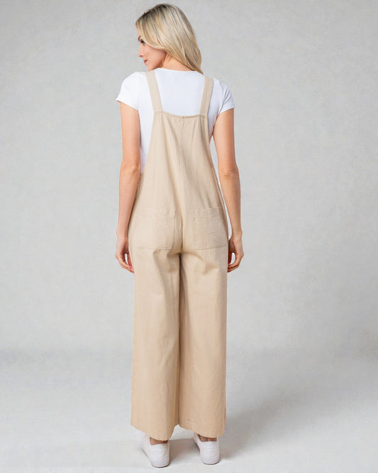 Woman wearing beige overalls on a plain background