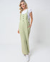 Woman wearing a light green jumpsuit with white sneakers on a white background