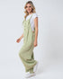Woman wearing a green jumpsuit and white sneakers on a white background