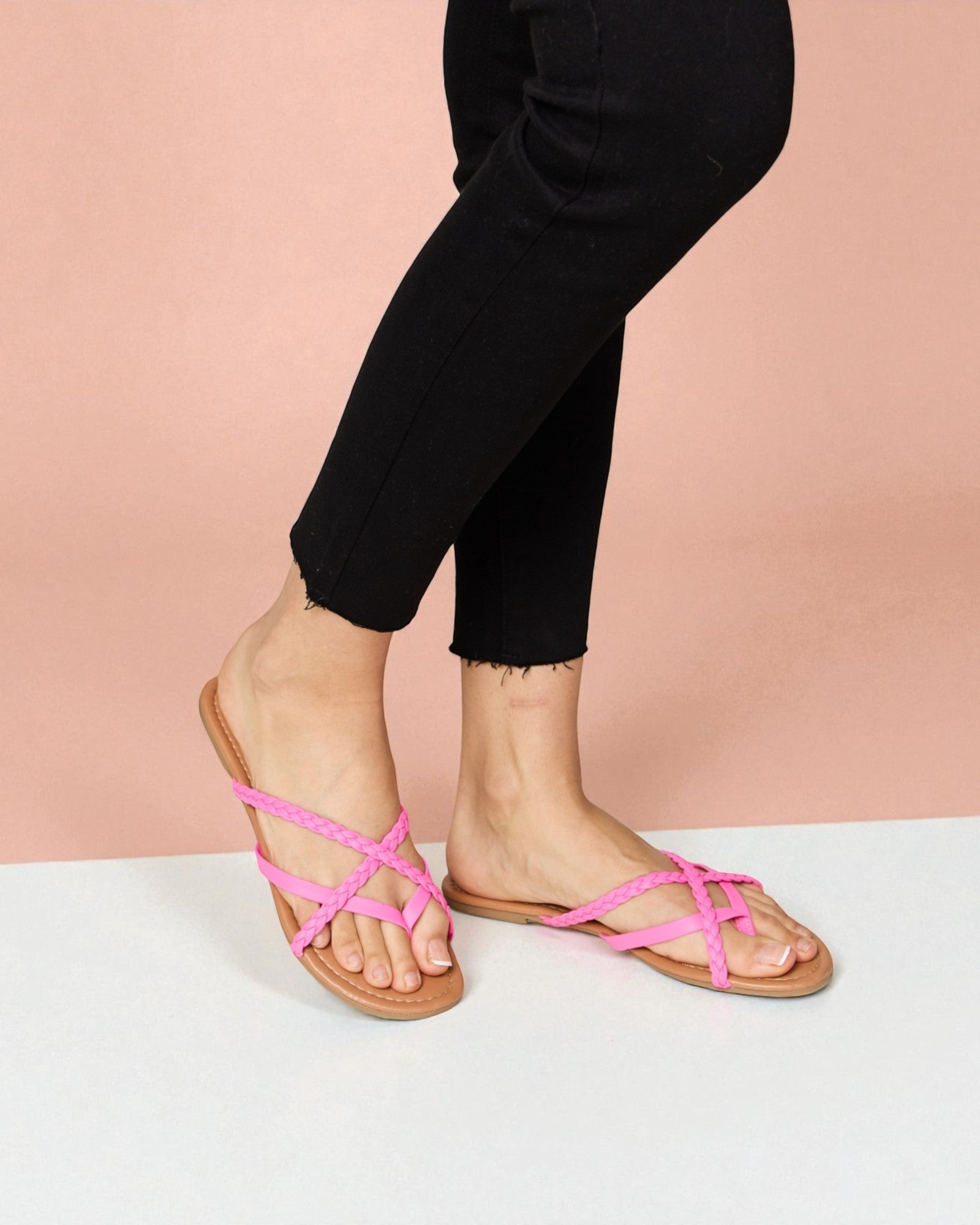 Person wearing pink sandals on a white surface with a pink background