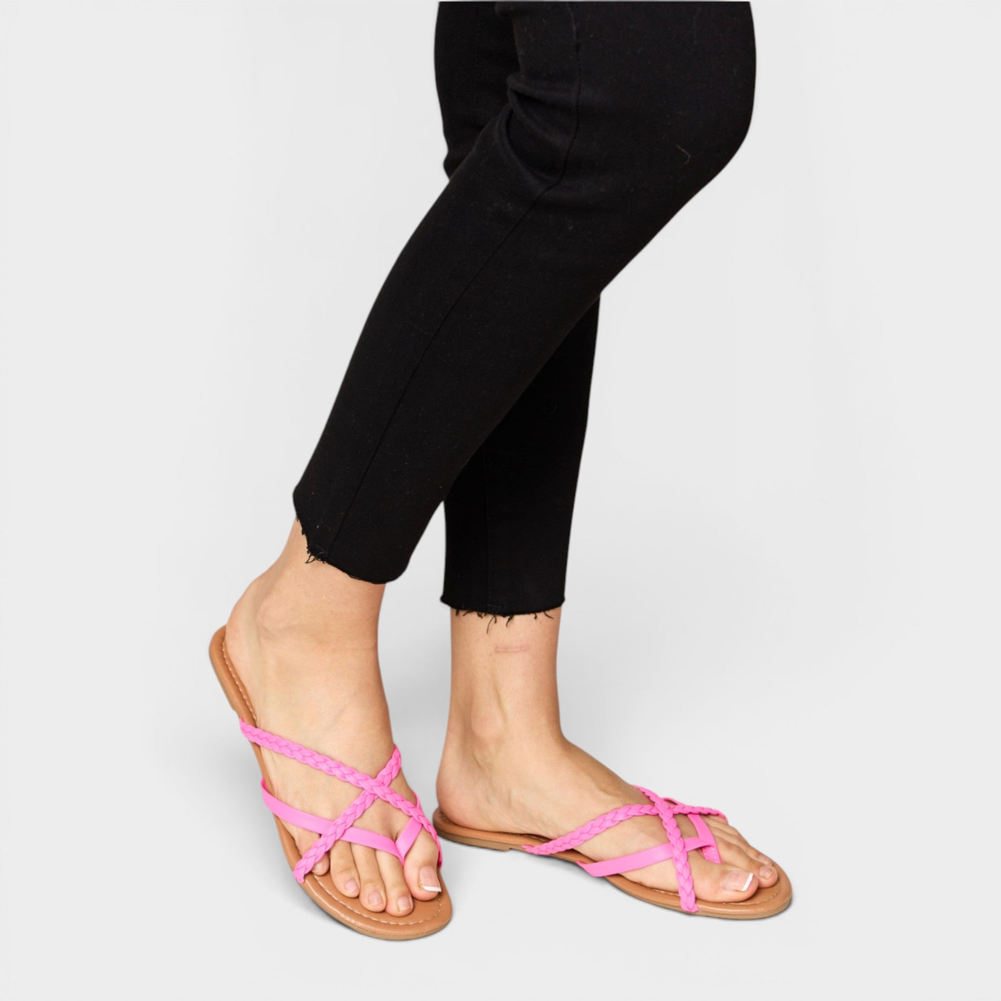 Person wearing black pants and pink sandals on a light gray background