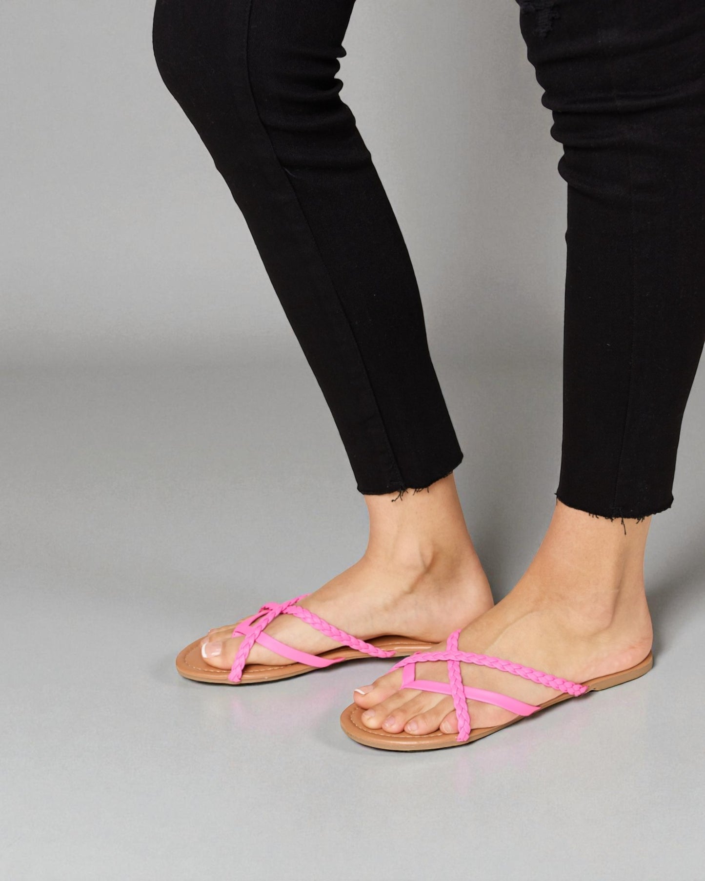 Person wearing black pants and pink sandals on a gray background