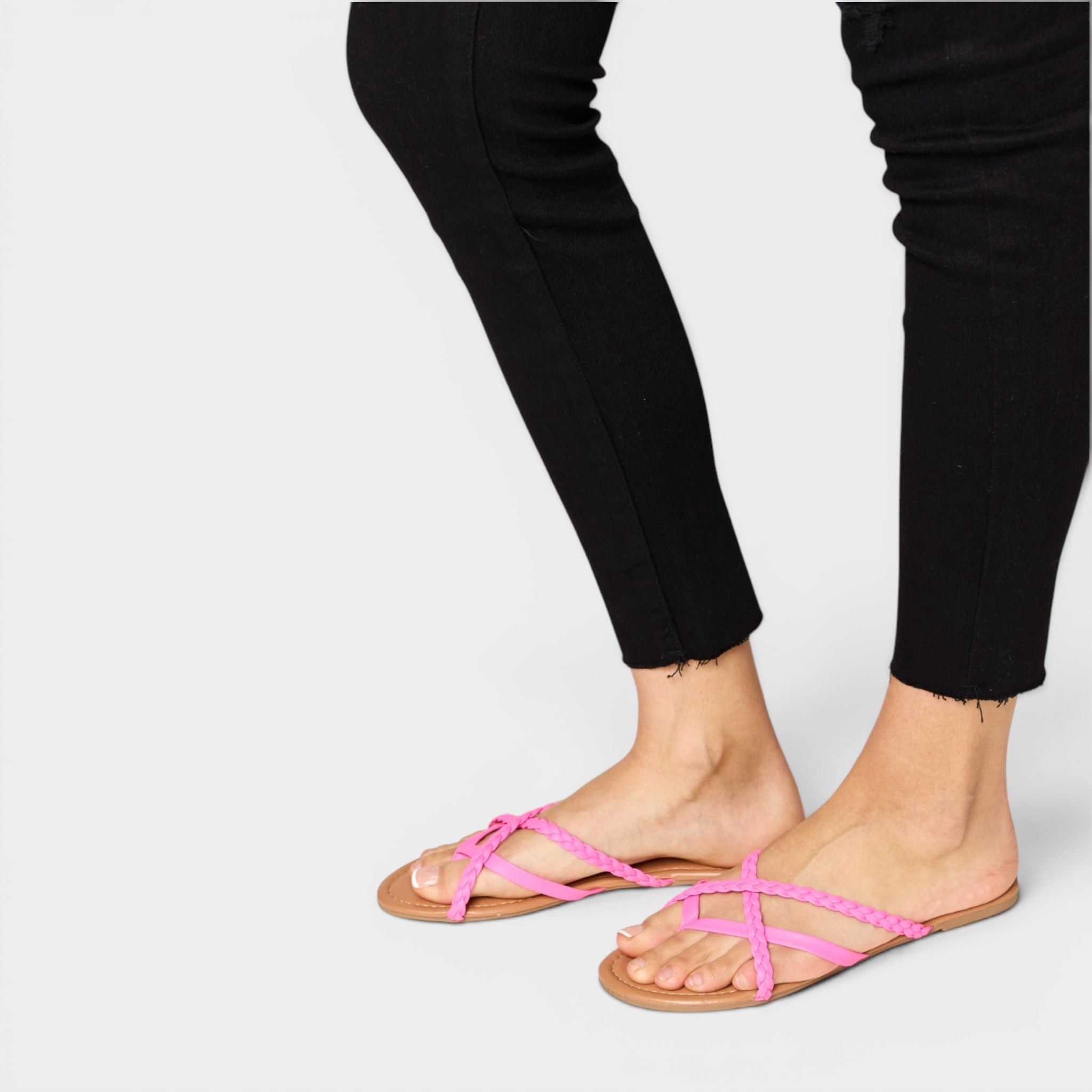 Person wearing black pants and pink sandals on a white background