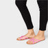 Person wearing black pants and pink sandals on a white background