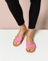 Person wearing black pants and pink sandals on a white background