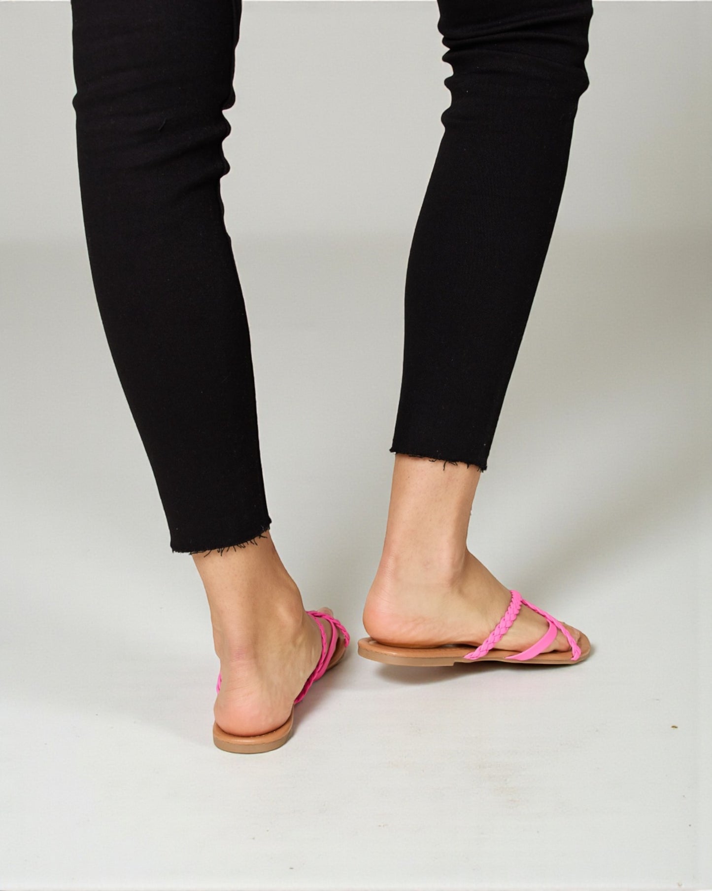 Person wearing black pants and pink sandals on a white background